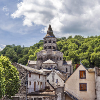 Basilica Notre Dame of Orcival seen from the village. Parts of old houses are at foreground. Puy-de-Dome department in French Auvergne.